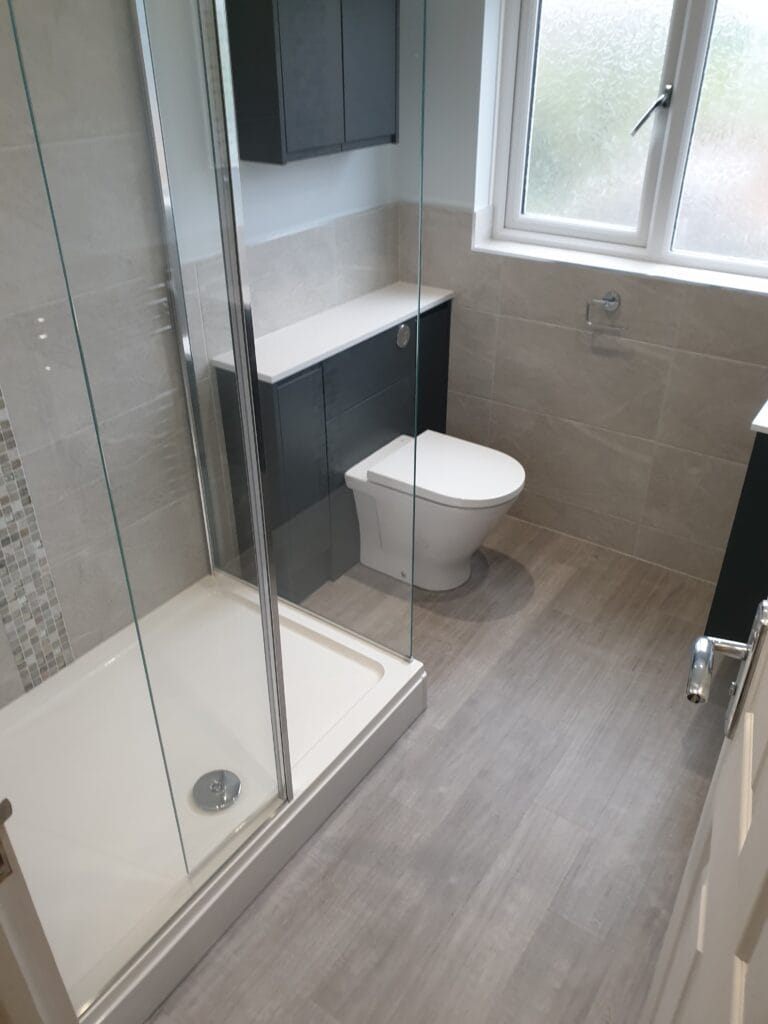 Modern en-suite with walk in shower , grey LVT flooring and dark Wc and basin unit - installation by Gregmar Bathrooms & Plumbing